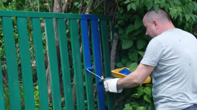 农村地区使用蓝色油漆的园丁绘画围栏