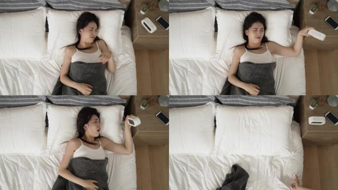 从上面看睡过头的亚洲妇女醒来时听到闹钟，带着震惊的脸急忙起床，因为她早上在家上班迟到了