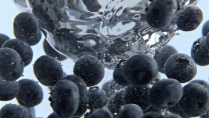 碳酸水多汁浆果在特写镜头内移动。在水中旋转的蓝莓