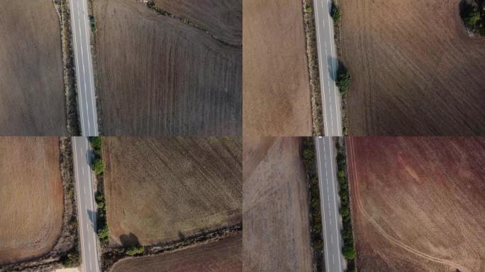 一条现代道路的航拍画面，两边都是无草的土地和五颜六色的树木