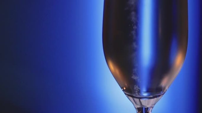 在蓝色背景中充满碳酸液体的香槟杯的宏观拍摄