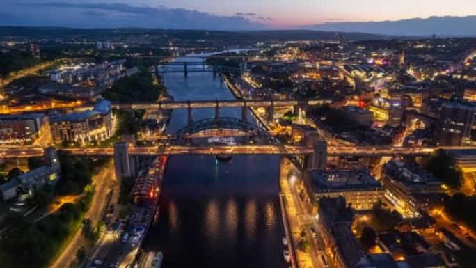 泰恩河的全景与标志性的泰恩桥和城市地区在晚上纽卡斯尔英国英格兰延时空中拍摄