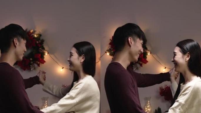 垂直屏幕: 快乐的亚洲夫妇在家里的圣诞晚会上跳舞。两个可爱的恋人男朋友和女朋友牵手放松享受圣诞夜在公