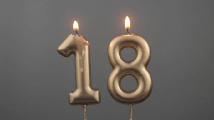 灰色背景上燃烧的金色生日蜡烛，编号18