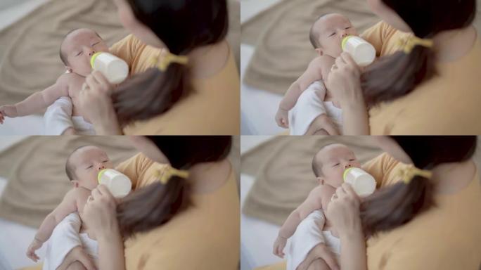 亚洲幼儿吃奶瓶牛奶，新生儿喂奶时与妈妈眼神交流，单身母亲在家养育婴儿，母亲职责关爱婴儿拥抱靠近乳房温