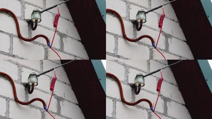 通过空气将电缆从电线杆连接到房屋。在房屋的墙壁上安装电气元件。正确的连接，电动休克的风险。