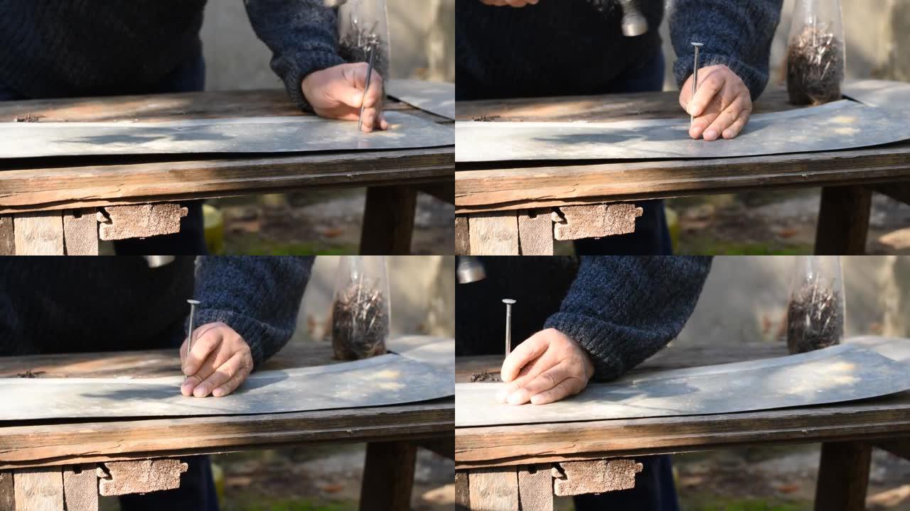 木匠用大钉子和锤子在金属上打孔。