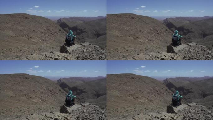 人坐在悬崖边，欣赏山景。摩洛哥托德拉峡谷。