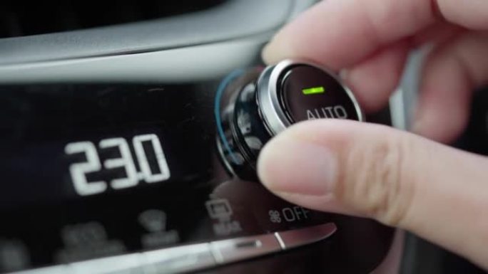 用手调节或转动的黑色汽车空调控制器温度调节的车辆仪表板特写