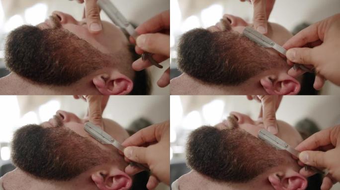 专业理发师用直剃刀刮顾客胡须。胡须切割