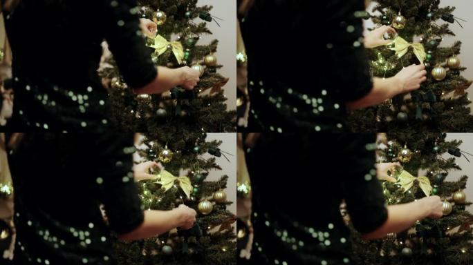 女性的手在圣诞树上挂灯。