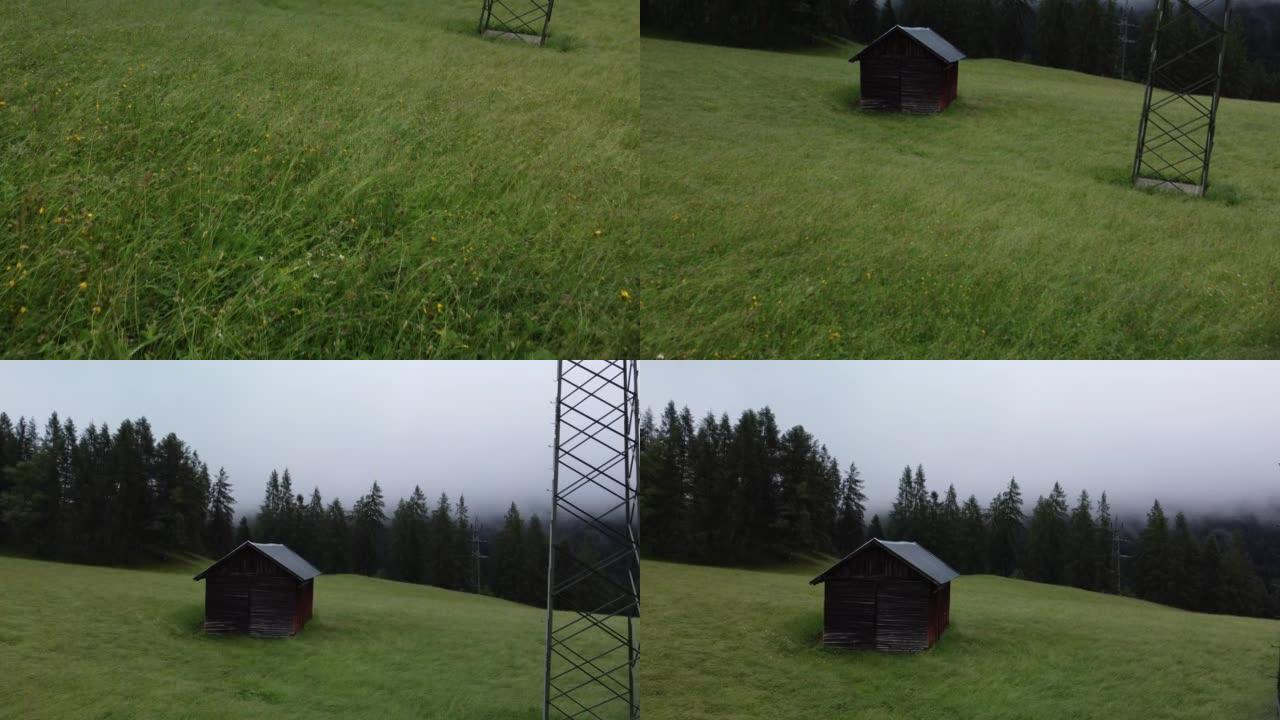 奥地利Reith bei Seefeld的绿色草地上的小屋，雾蒙蒙的日子里有林木