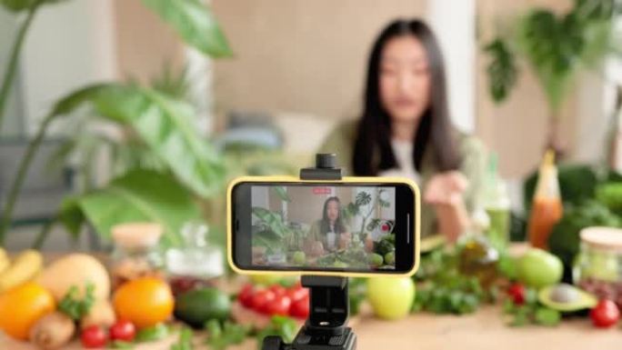 亚洲女性博客作者在智能手机上录制有关食谱如何烹饪健康沙拉的视频课程