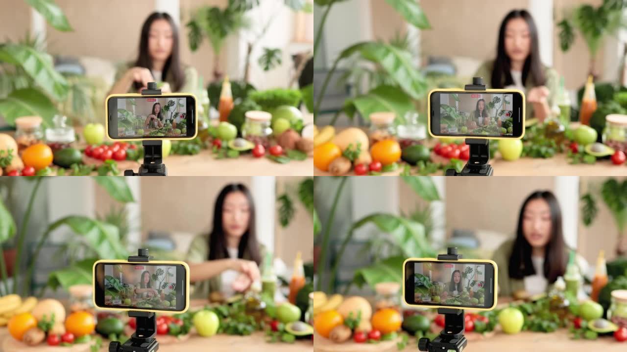 亚洲女性博客作者在智能手机上录制有关食谱如何烹饪健康沙拉的视频课程