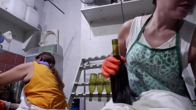 在当地一家小型酿酒厂的团队中工作的两个女人，一个是封盖瓶子，另一个是装瓶葡萄酒