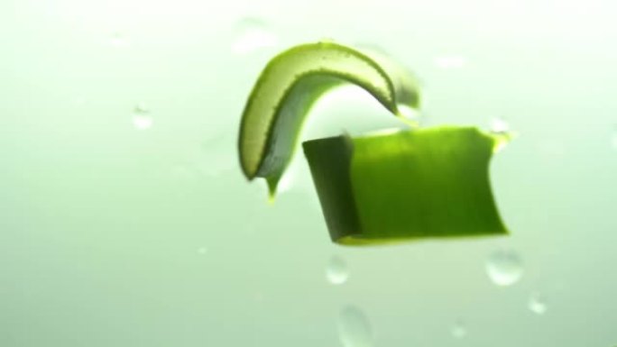 俯视图，芦荟片。移液器与芦荟汁滴在绿色背景上多汁的芦荟叶切片上。天然化妆品的概念。