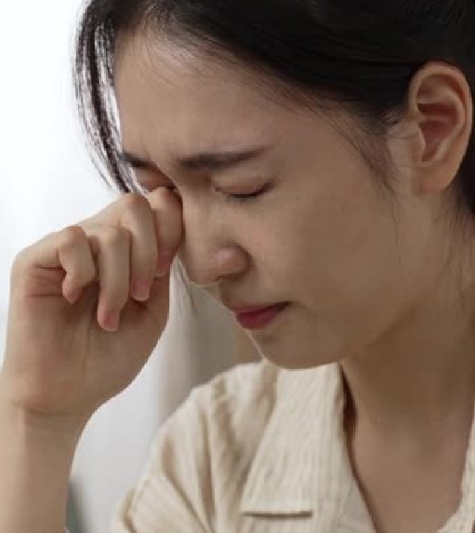垂直屏幕: 一位过度劳累的亚洲女企业家在笔记本电脑上在家工作时闭上痛苦的干涩眼睛的特写镜头