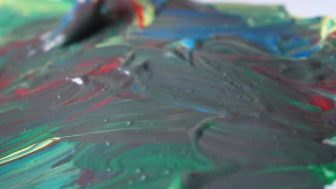 艺术家将不同颜色的油漆与画笔混合在一起进行绘画。准备绘制图片的颜色。艺术家通过结合调色板上已经拥有的