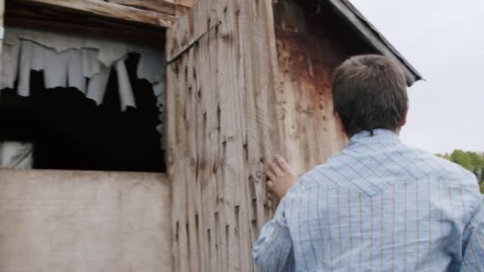 年轻的牧场主男孩在美国科罗拉多州一个小镇家庭拥有的牧场上的木制鸡舍或外部存储棚上解锁并打开门