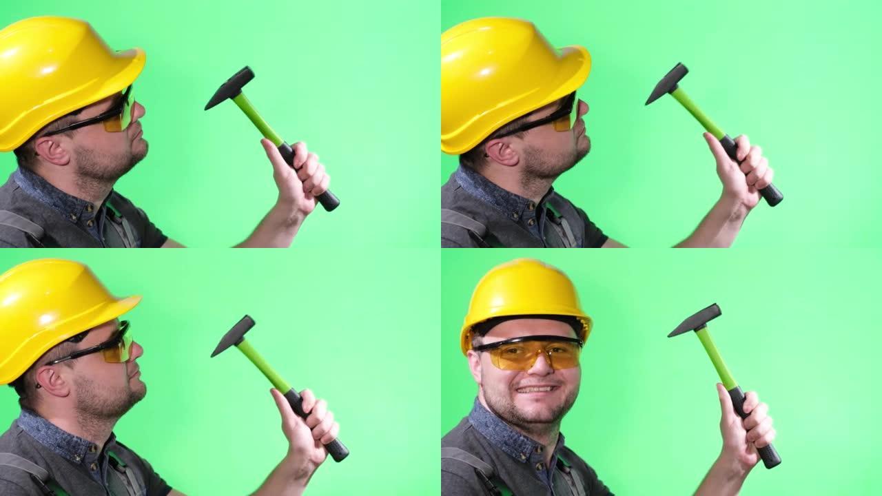 穿着黄色头盔和护目镜的男性建造者，用锤子工作，绿色背景上的chromakey，