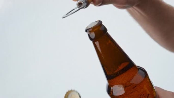 用开瓶器打开啤酒瓶的男子用超慢动作特写。
