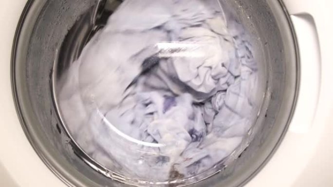 洗衣机的旋转滚筒清洗脏床单的特写镜头。