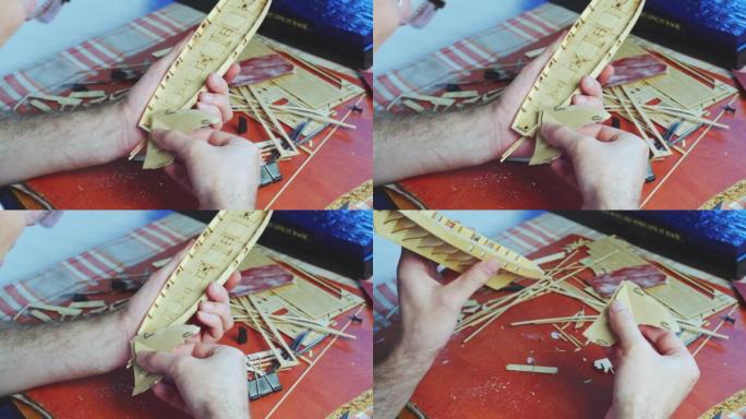 人手调整船模的胶合板细节，在砂纸上打磨。建造玩具船、爱好和手工艺品的过程。工作台有各种材料、零件和工