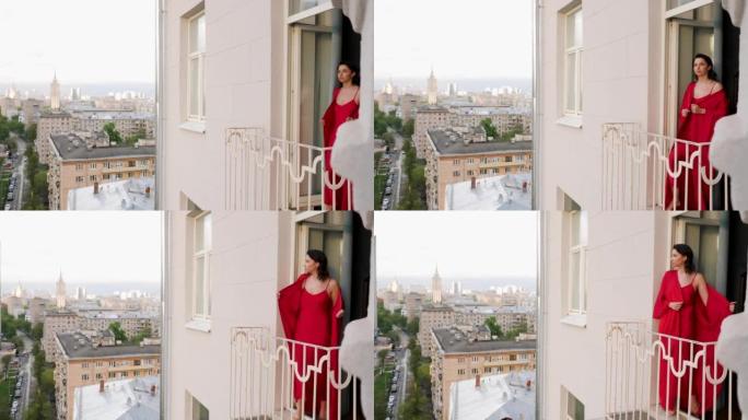 穿着红色丝绸长袍的女人在莫斯科高楼的阳台上出门。