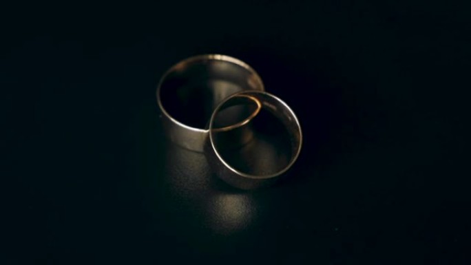 两个金色结婚戒指在黑色背景上旋转。