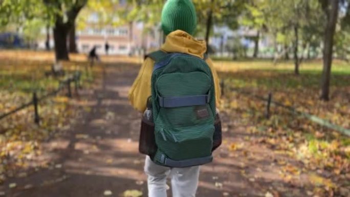 穿着黄色夹克的男孩带着绿色背包去上学