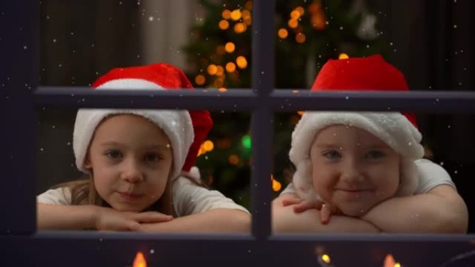 圣诞树背景上的女孩晚上看着冬天窗外的雪