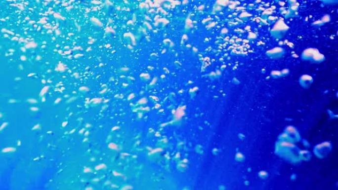 水下深蓝色海洋水景，海面上有气泡和阳光。慢动作