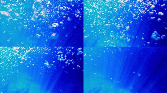 水下深蓝色海洋水景，海面上有气泡和阳光。慢动作