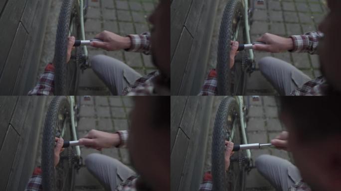 在街头自行车停车场修理自行车车轮的家伙。德国户外用小型手泵抽水轮胎。骑自行车的人使用手动工具，自行车