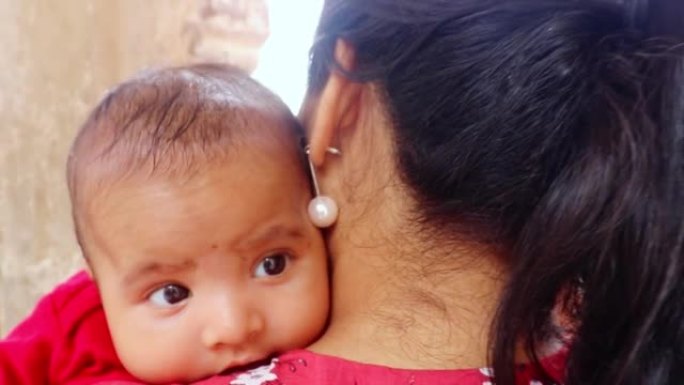 可爱的婴儿眼神从平面角度靠在母亲的肩膀上