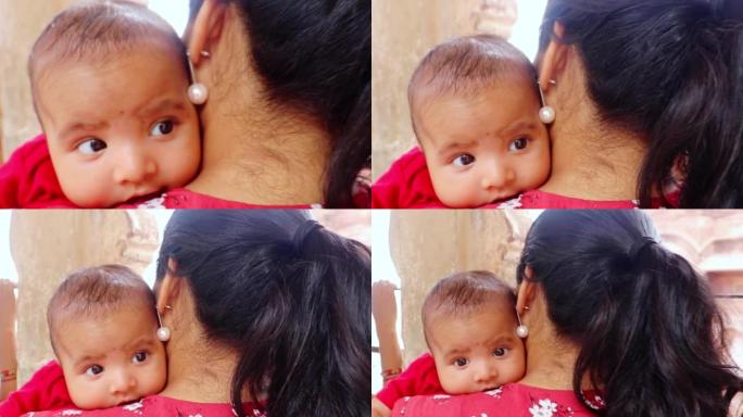 可爱的婴儿眼神从平面角度靠在母亲的肩膀上
