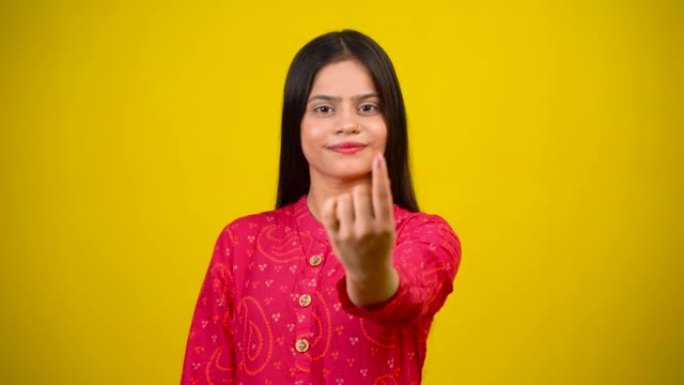 年轻的印度女孩在投票后伸出手指，开朗的女孩被隔离在黄色背景中