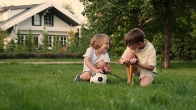 两个快乐朋友的孩子用泵给足球充气。