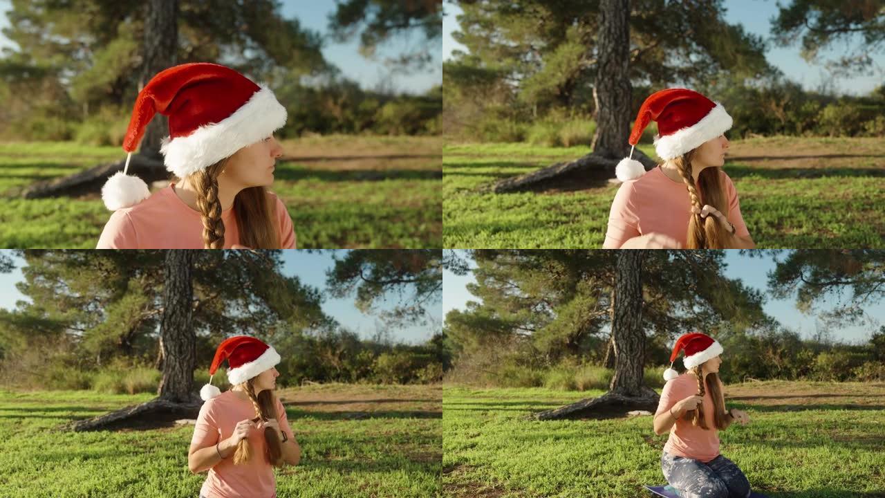 我把头发编成辫子，一个戴着红色圣诞老人帽子的女孩。圣诞节在树林里瑜伽。