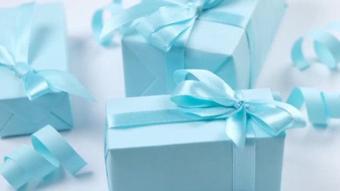 蓝色背景上带有蓝色蝴蝶结的旋转蓝色礼品盒，庆祝男孩或男人的生日，聚会或周年纪念日或新生儿的概念