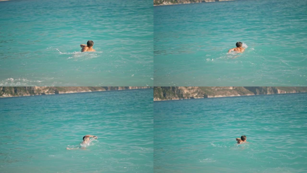 后视图运动员运动员在爱琴海奥鲁德尼兹海滩的地中海绿松石水中游泳。夏季旅游季节费特希耶，穆拉土耳其。积