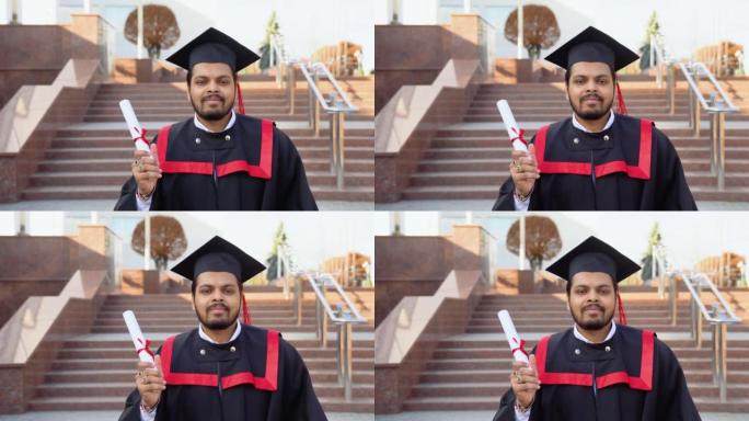 快乐的毕业生。穿着毕业礼服的快乐印度男子持有文凭