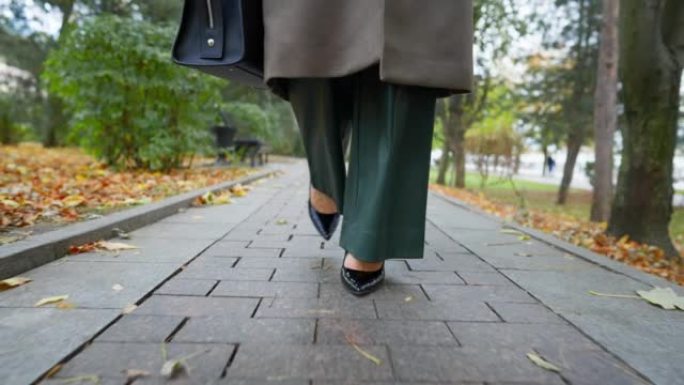 在阴云密布的秋日，穿着高跟鞋的美腿女商人走在路上