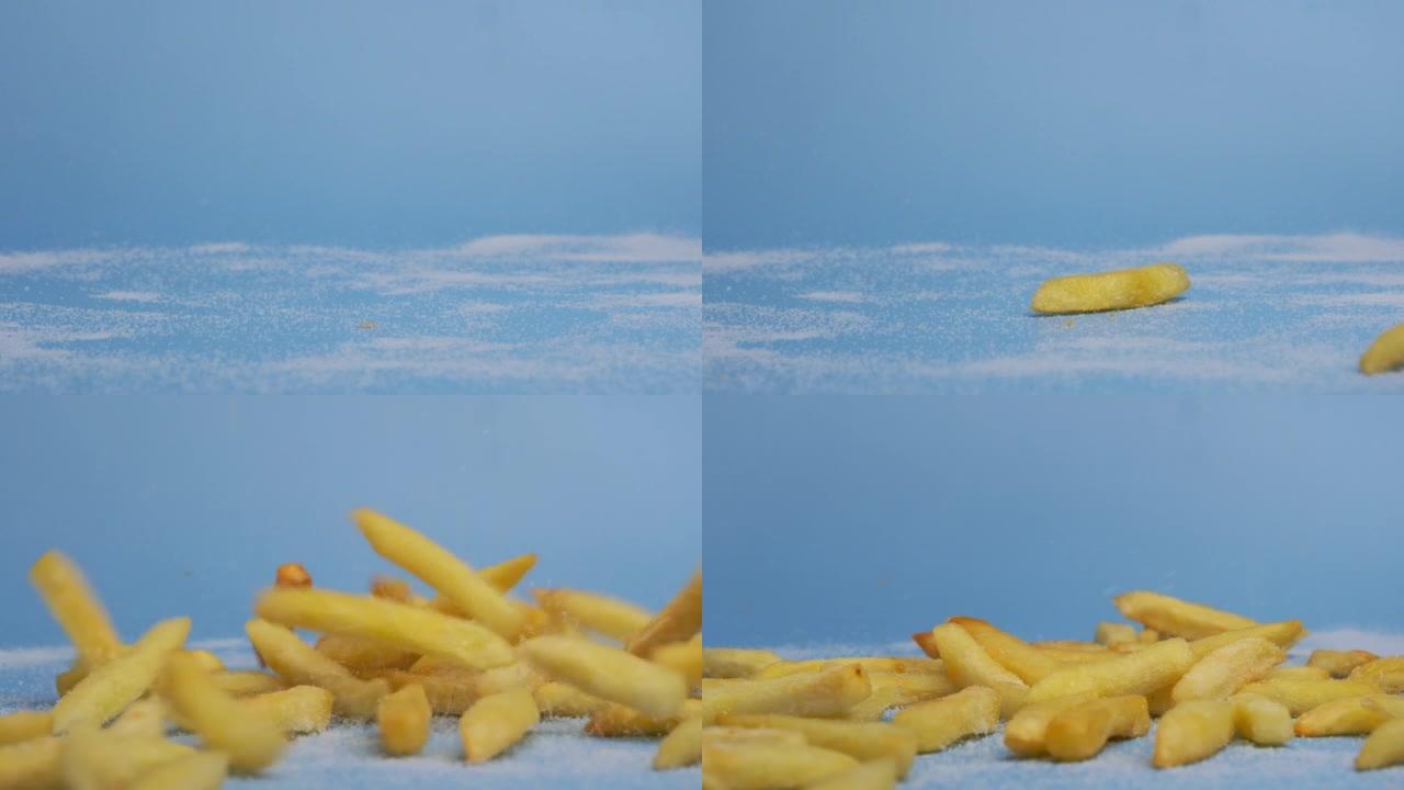 新鲜薯条落在蓝色背景上的照片。在厨房准备自制炸薯条或薯片。垃圾食品。