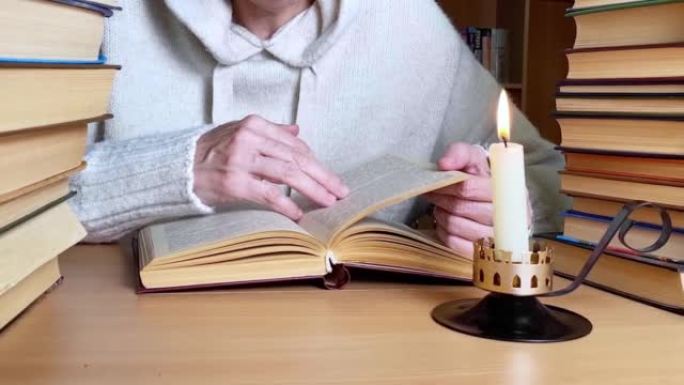 在点着蜡烛的图书馆桌子上，手翻着书，背景是书架