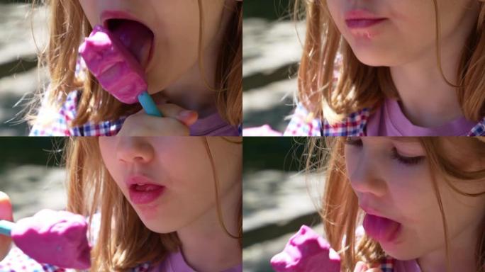 特写。一个金发小女孩在公园里吃粉红色的冰淇淋。