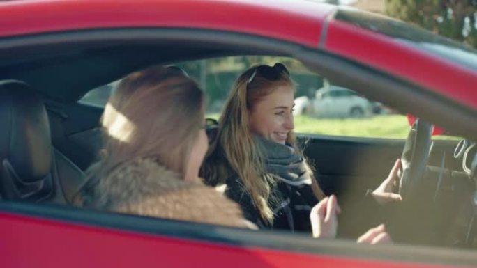 漂亮的女人在红色跑车内聊天，两个女性朋友准备周末旅行和娱乐，迷人的年轻女人在开着窗户的车内听音乐，说