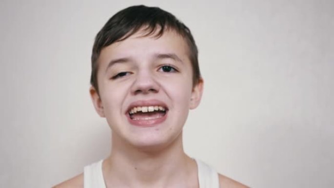 微笑的少年用嘴打手势，露出他的牙齿，舌头。特写