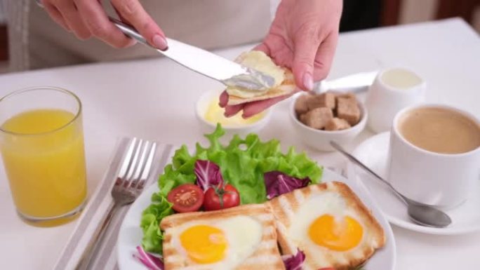 女人在桌子上的烤面包上涂抹黄油，搭配美味的蛋蛋烤面包早餐