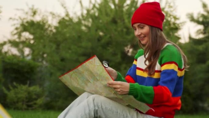戴着红帽子的年轻女子检查地图。一名白人妇女用放大镜检查地图。